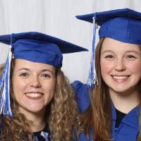 Two friends in their cap and gowns pose together for a photo at GradFest